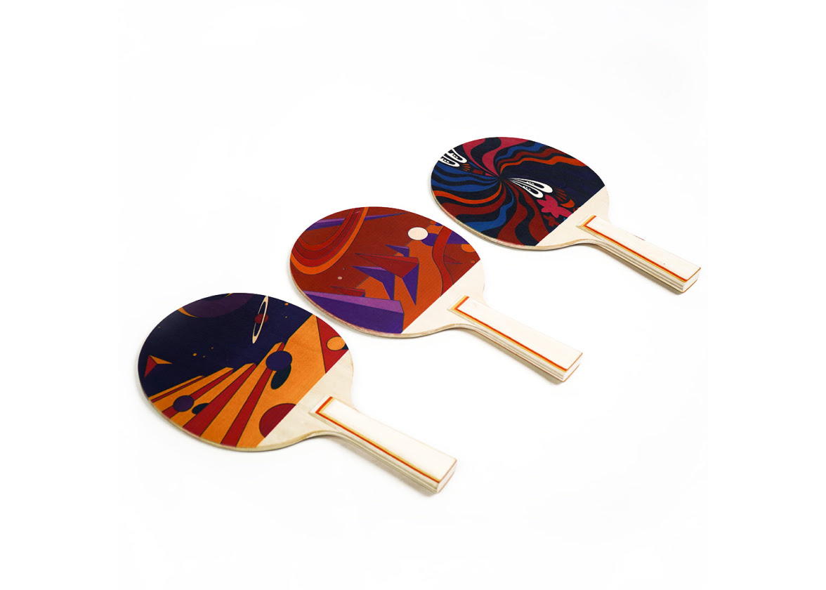 Three wooden table tennis bats at an angle with colourful printed geometric shapes.