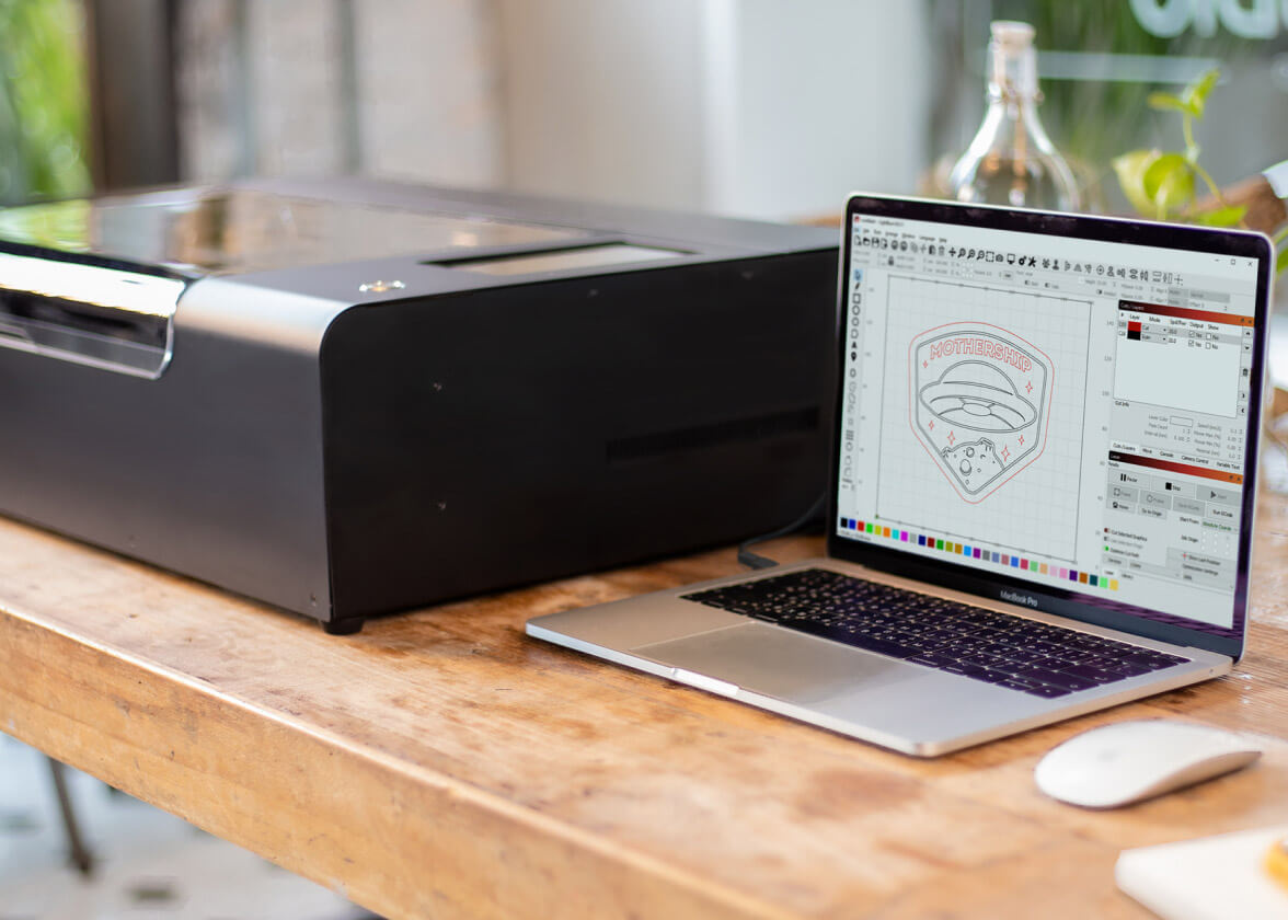 LightBurn running on a laptop next to a Beamo on a wooden desk.