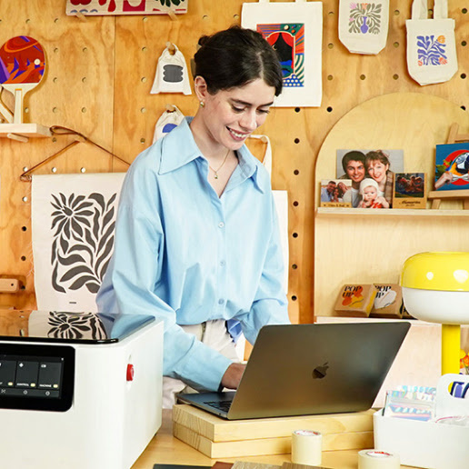 A woman smiling at her computer with a FLUX Ador next to it.